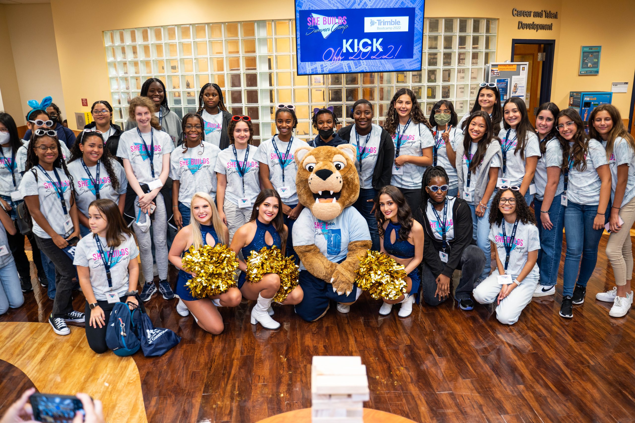 young ladies participating in the summer camp She Builds standing by side Roary and cheerleaders